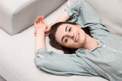 Smiling woman relaxing on sofa, above view