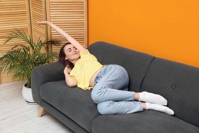 Photo of Beautiful woman stretching on sofa at home