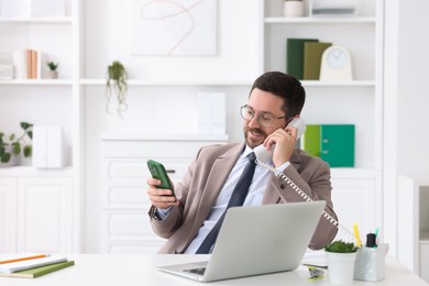 Photo of Smiling businessman working at table in office