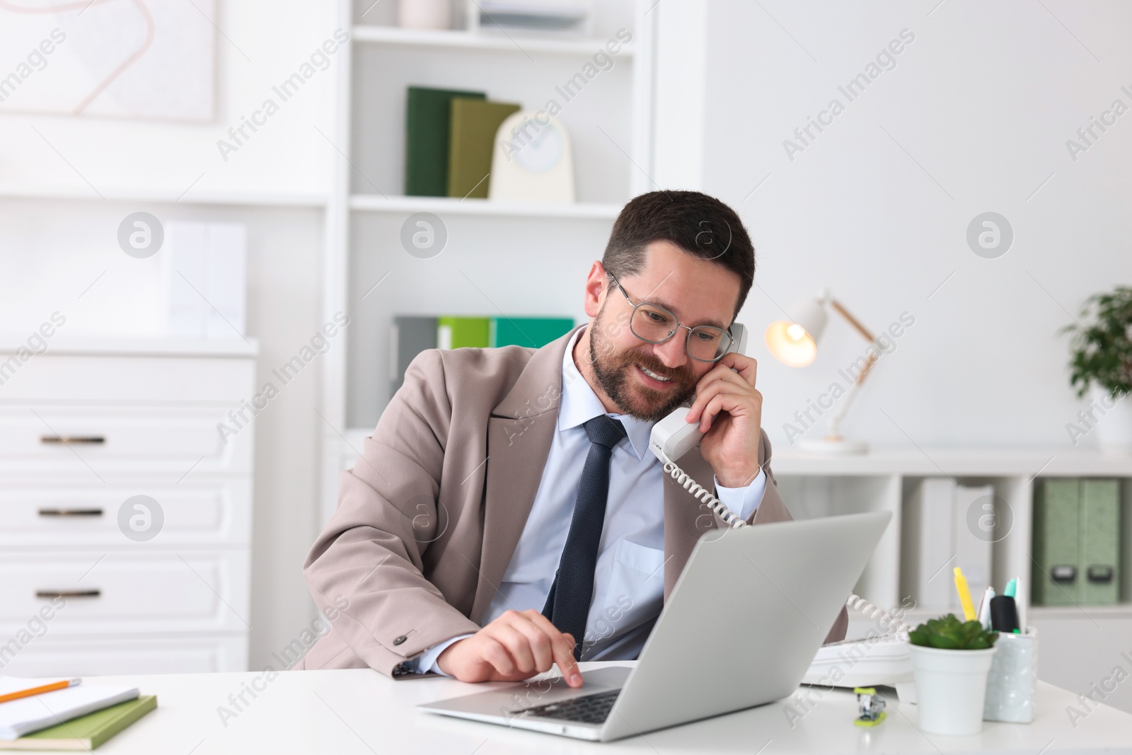 Photo of Smiling businessman working at table in office