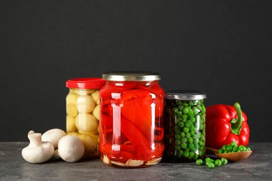 Photo of Different pickled products in jars on grey textured table