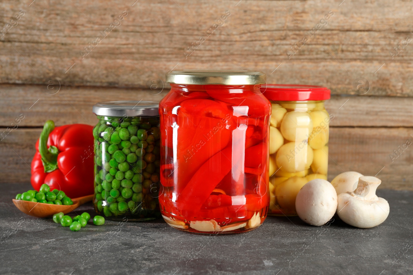 Photo of Different pickled products in jars on grey textured table