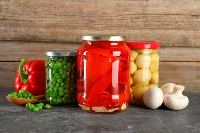 Photo of Different pickled products in jars on grey textured table