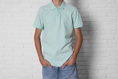 Photo of Teenage boy wearing light green t-shirt near white brick wall, closeup