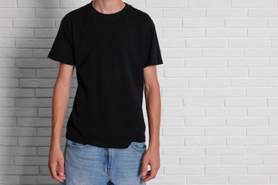 Photo of Teenage boy wearing black t-shirt near white brick wall, closeup. Space for text