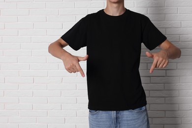 Photo of Teenage boy wearing black t-shirt near white brick wall, closeup