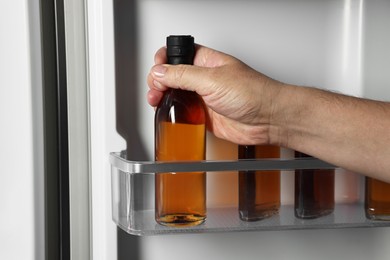 Woman taking bottle with drink from refrigerator, closeup