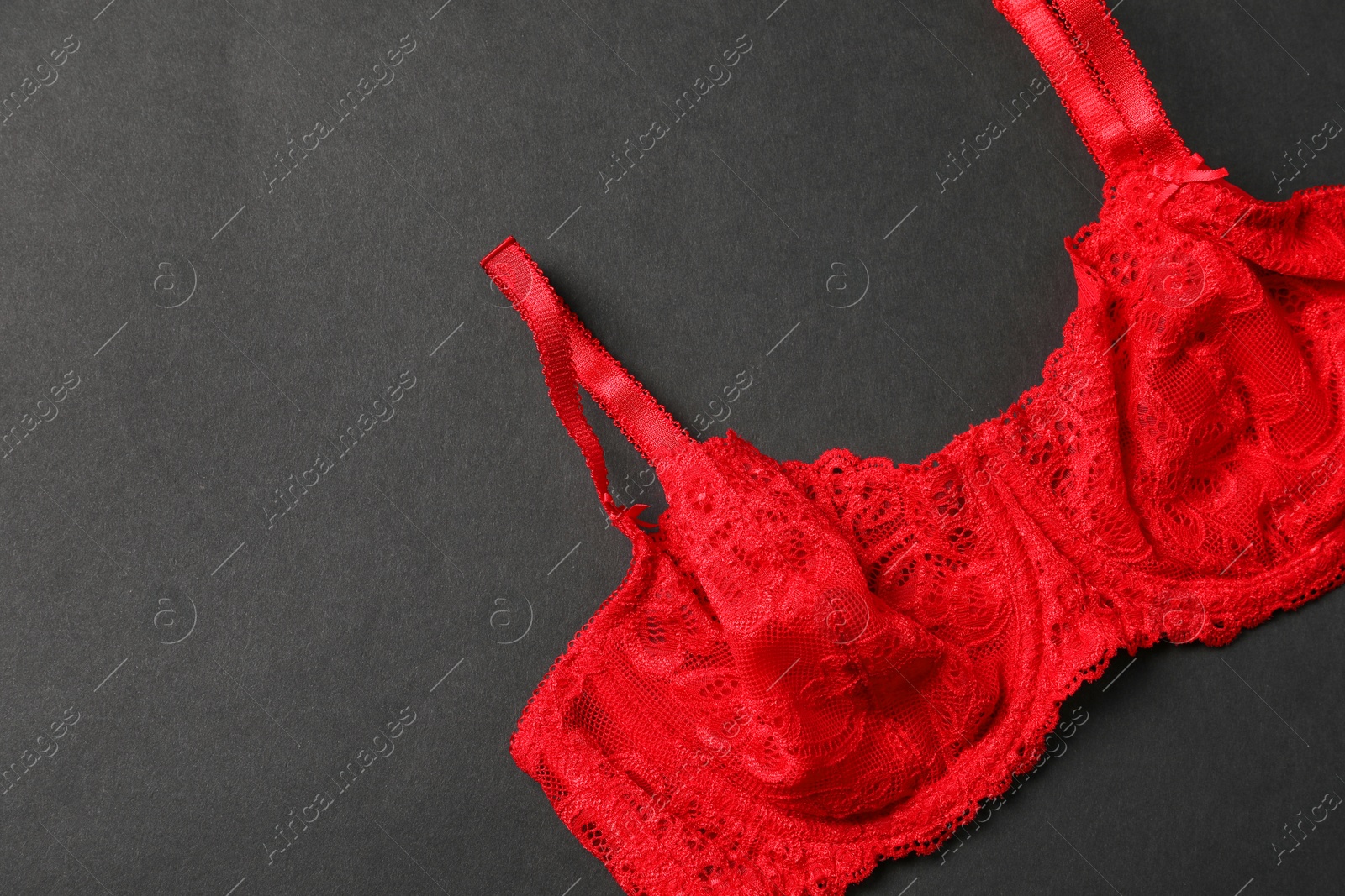 Photo of Beautiful lace bra on black background, top view. Space for text