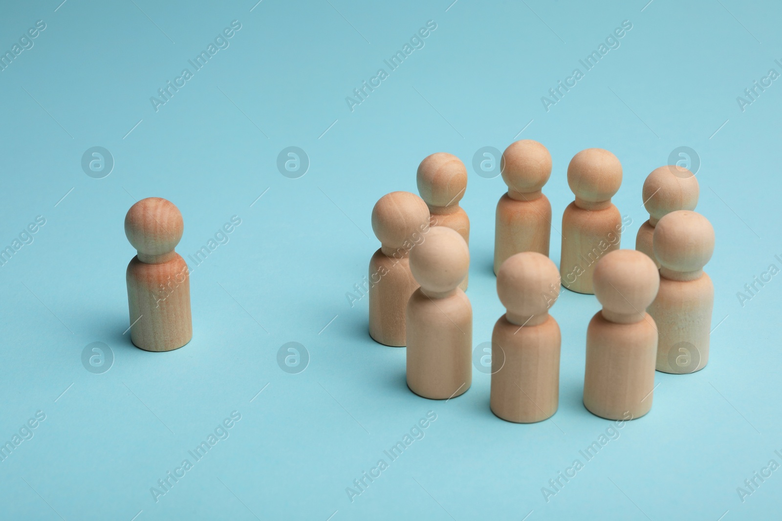 Photo of Loneliness concept. Human figure distant from others on light blue background