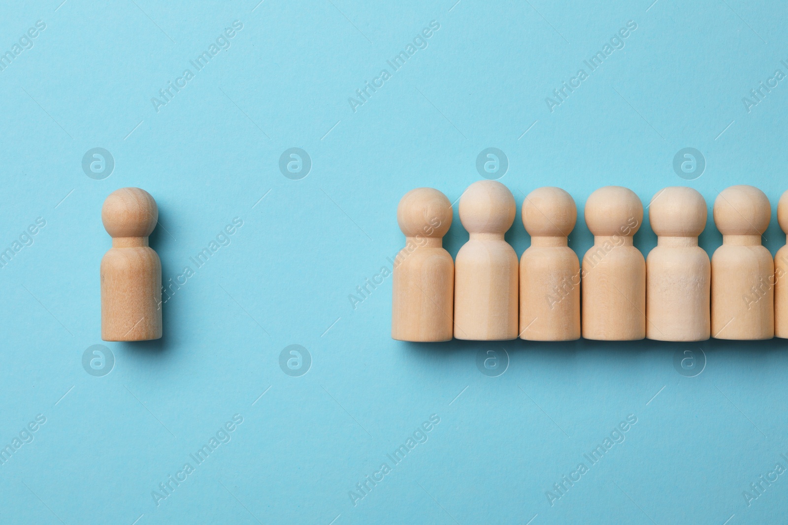 Photo of Loneliness concept. Human figure distant from others on light blue background, top view