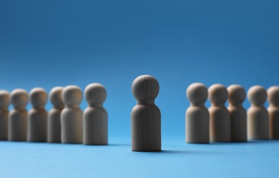 Photo of Loneliness concept. Human figure distant from others on blue background