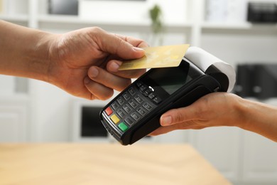 Customer paying with credit card using POS machine indoors, closeup