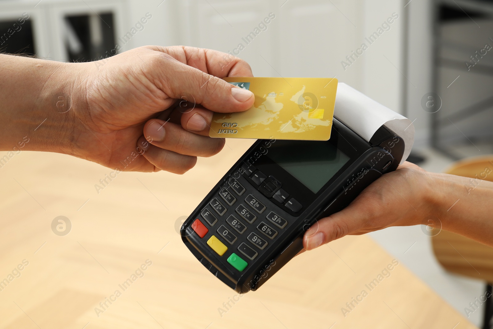 Photo of Customer paying with credit card using POS machine indoors, closeup