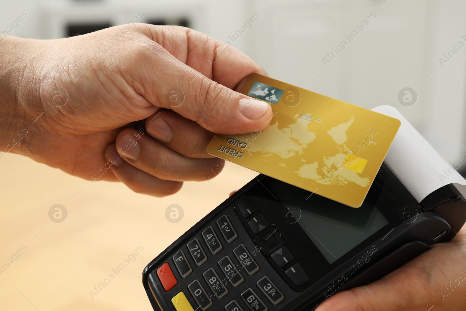 Photo of Customer paying with credit card using POS machine indoors, closeup