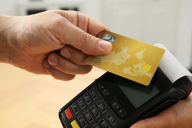 Customer paying with credit card using POS machine indoors, closeup