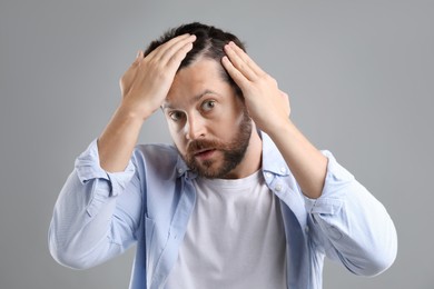 Photo of Man with hair loss problem on gray background