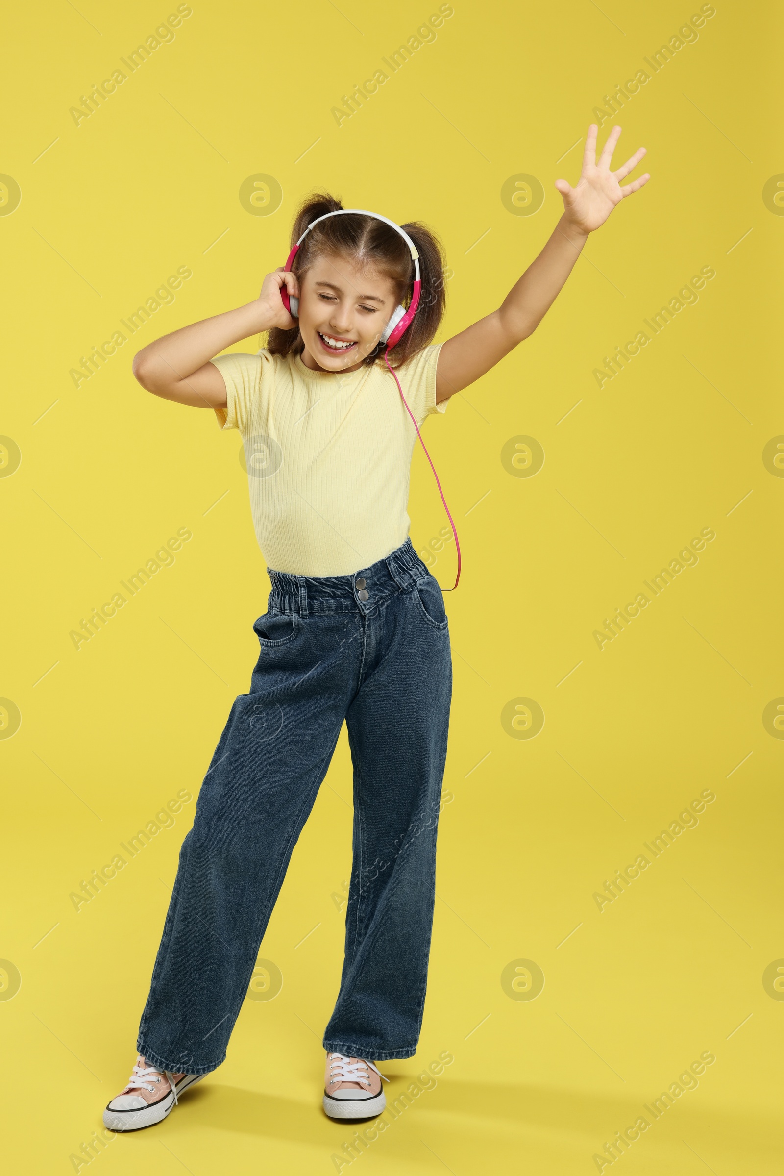 Photo of Cute girl listening to music on yellow background