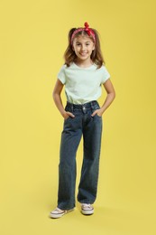 Full length portrait of cute girl on yellow background