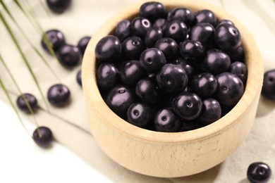 Photo of Ripe acai berries in bowl on white table, closeup