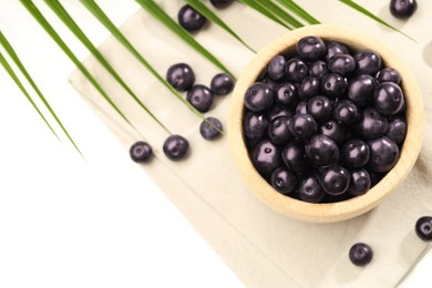 Photo of Ripe acai berries in bowl on white table, flat lay. Space for text