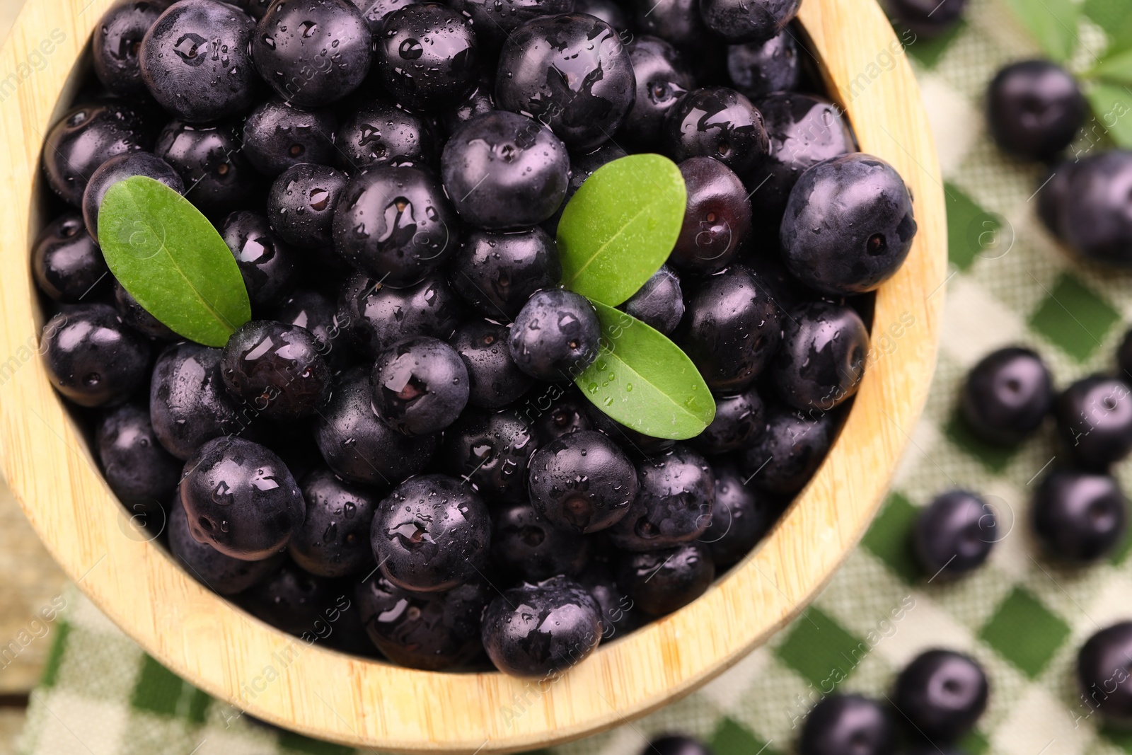 Photo of Ripe acai berries and leaves in bowl on table, top view