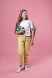 Photo of Teenage girl with backpack and books on pink background