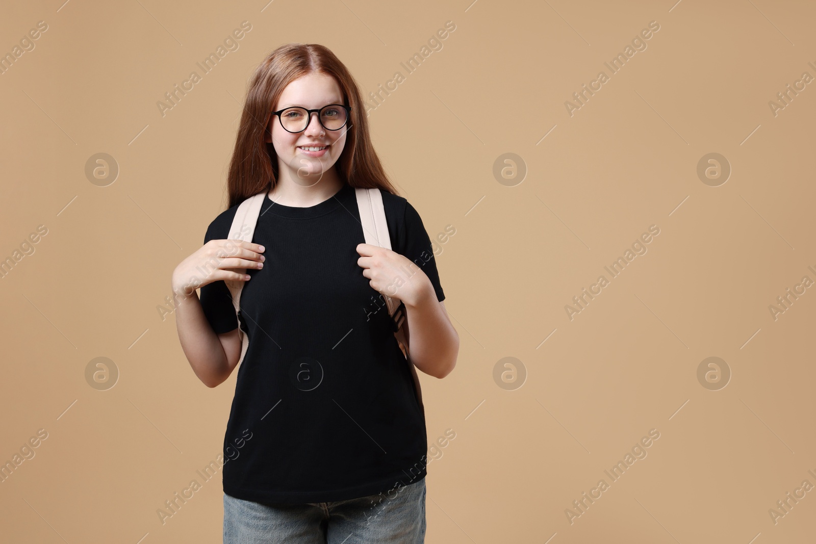 Photo of Teenage girl with backpack on beige background, space for text