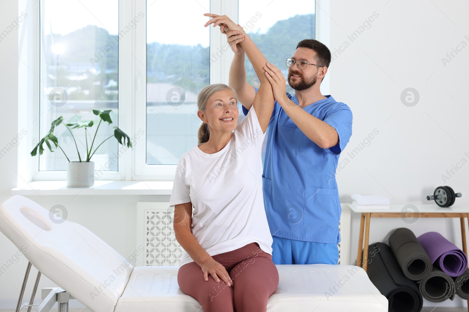 Photo of Physiotherapist working with senior patient in rehabilitation center