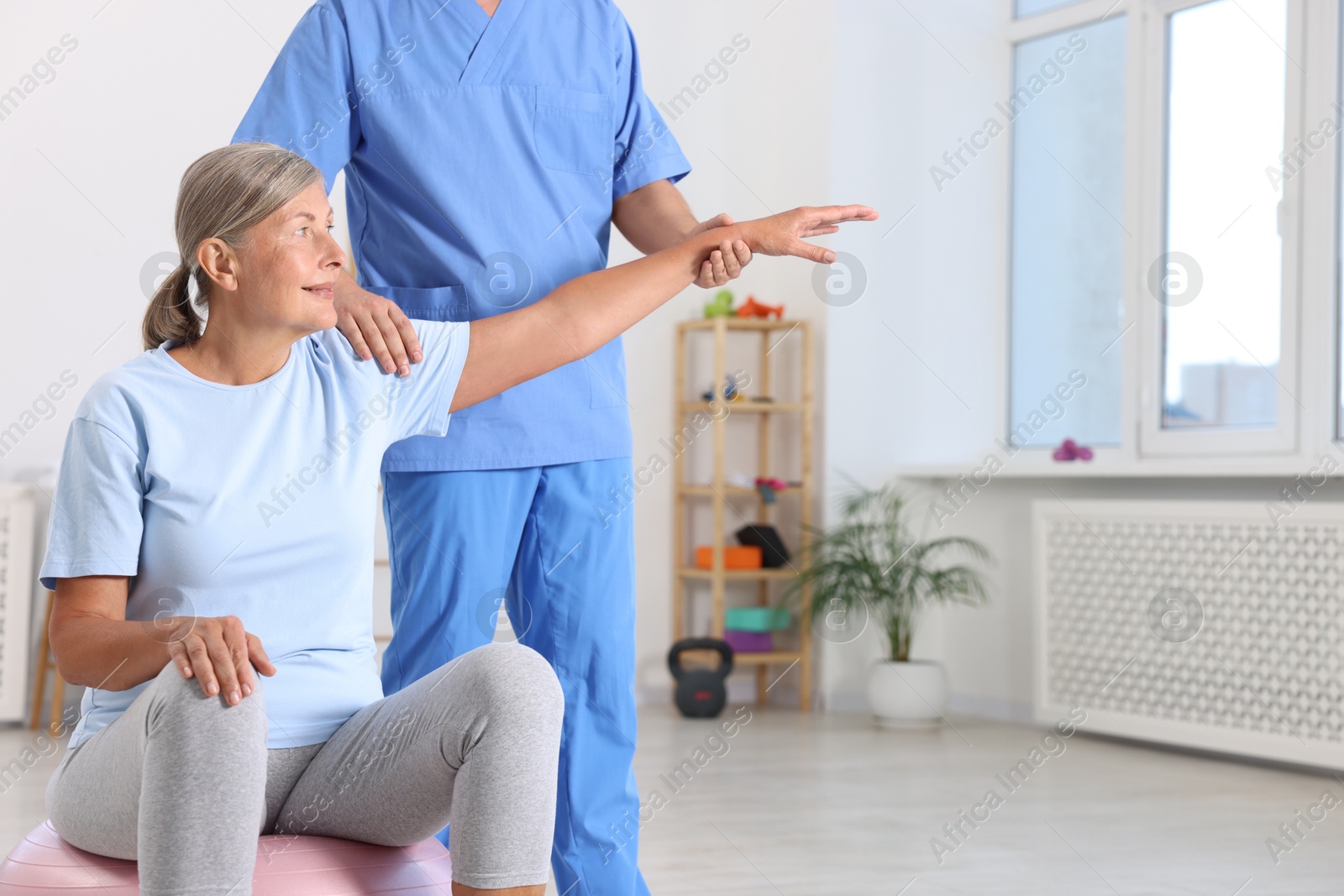 Photo of Physiotherapist working with senior patient in rehabilitation center