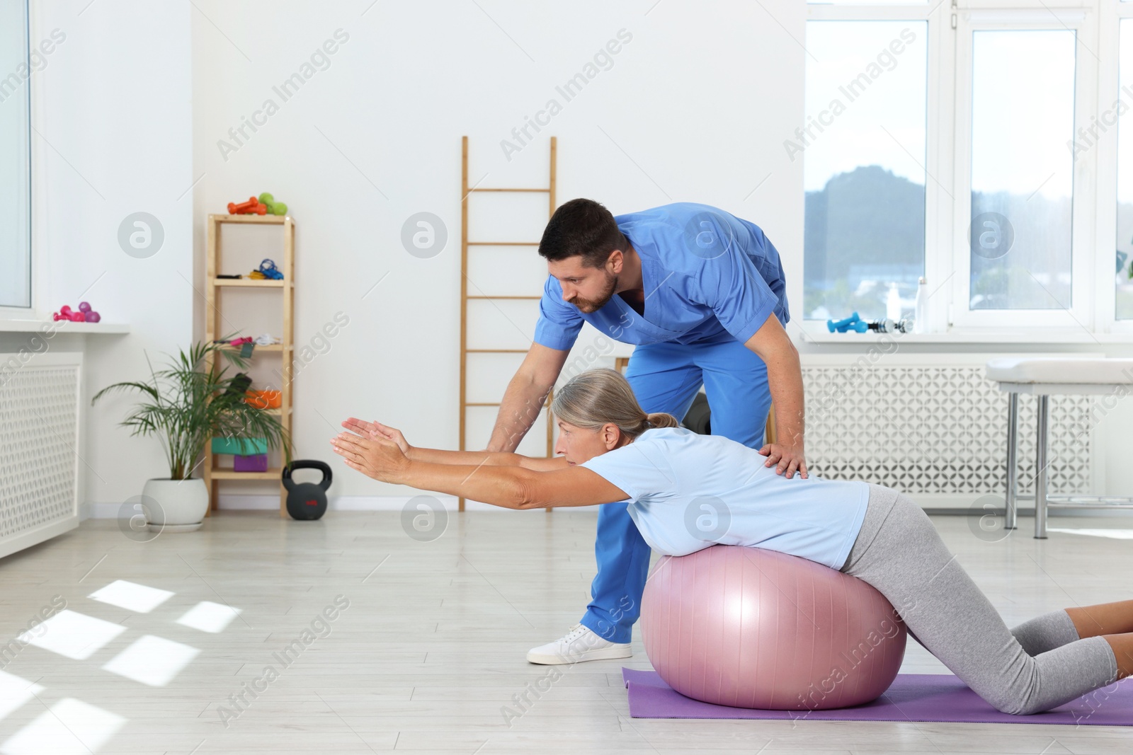 Photo of Physiotherapist working with senior patient in rehabilitation center