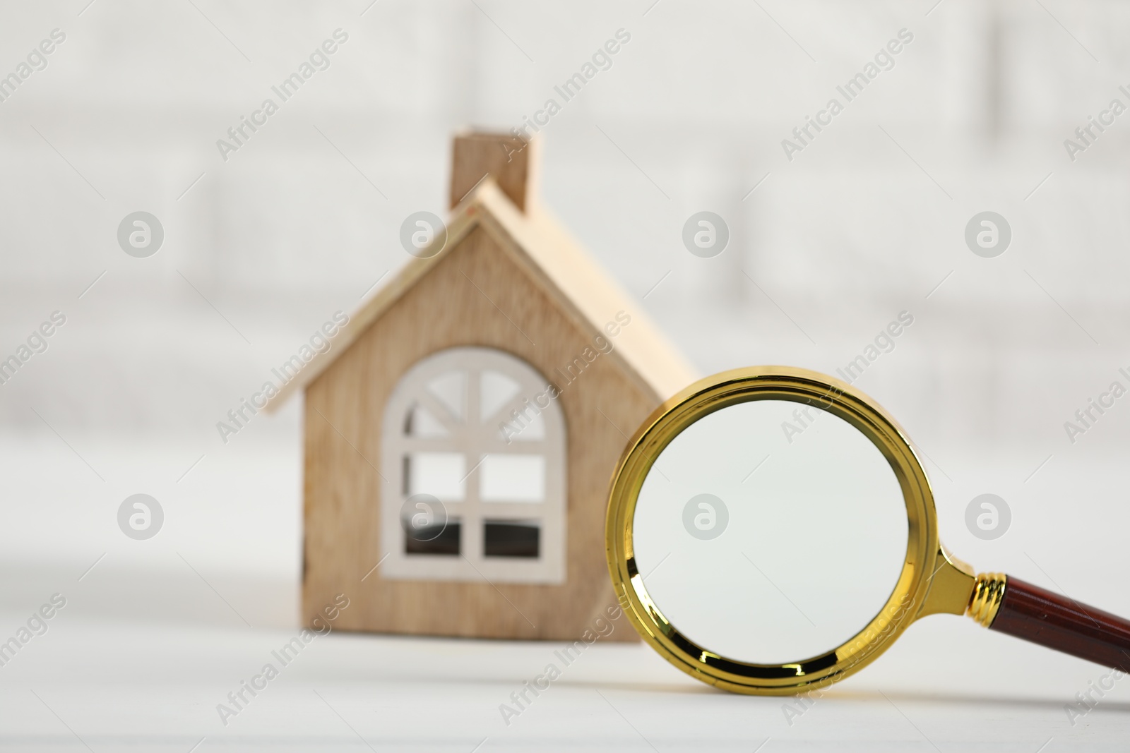 Photo of House hunting. Magnifying glass and house figure on white table, selective focus