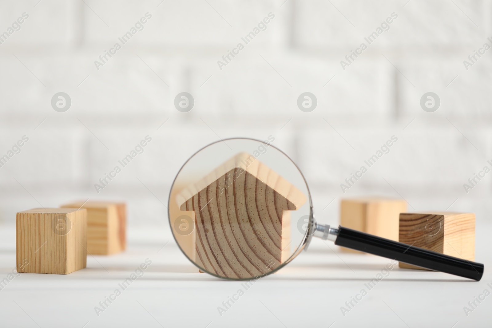 Photo of House hunting. Magnifying glass and house figure on white table