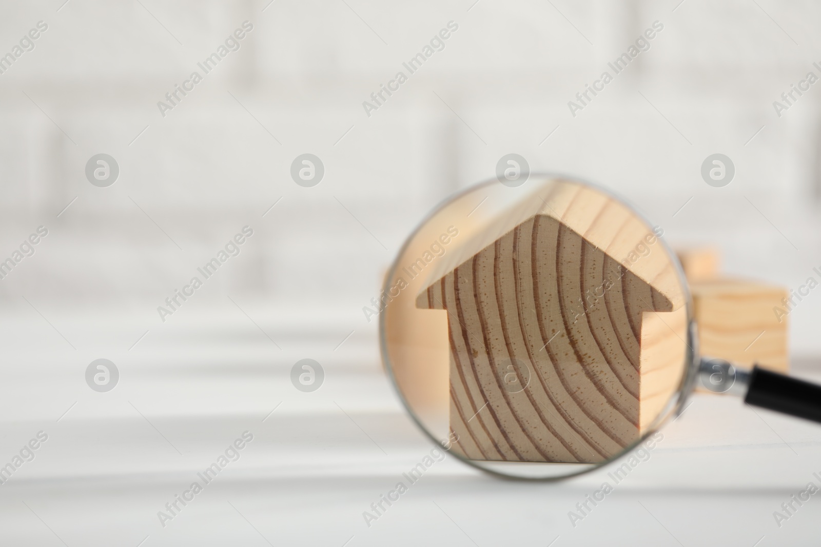 Photo of House hunting. Magnifying glass and house figure on white table, space for text