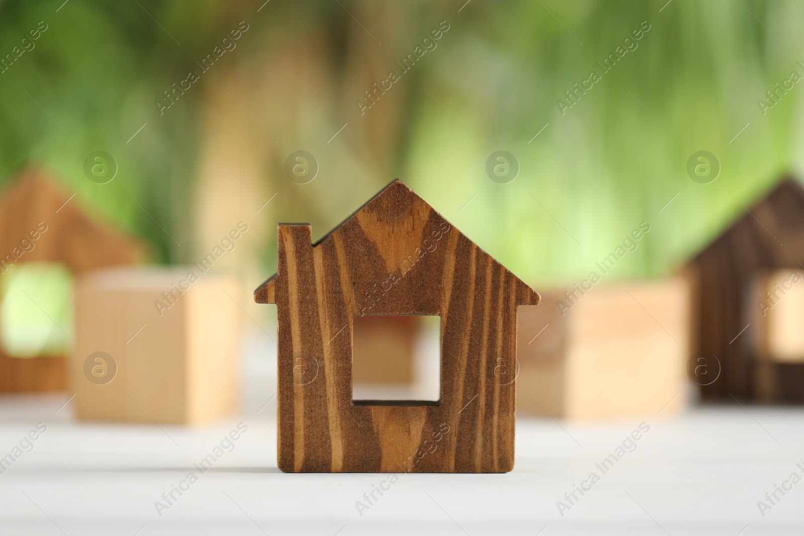 Photo of House hunting. Wooden house figure on white table