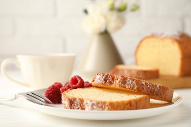 Photo of Freshly baked sponge cake and raspberries on white wooden table, closeup