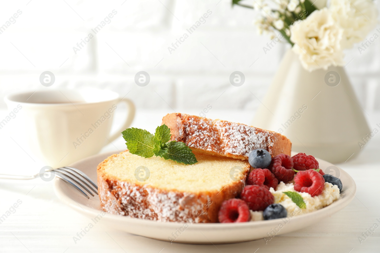 Photo of Freshly baked sponge cake, whipped cream, berries and mint on white wooden table