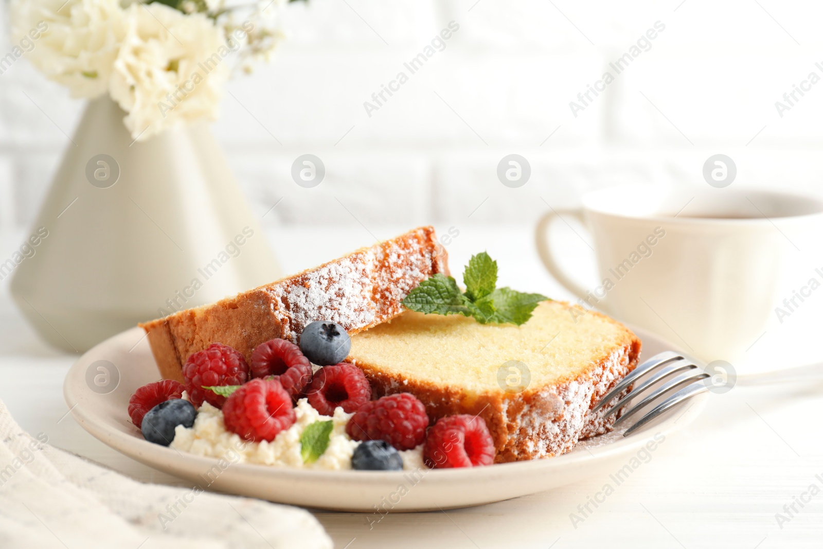 Photo of Freshly baked sponge cake, whipped cream, berries and mint on white wooden table, closeup