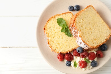 Photo of Freshly baked sponge cake, whipped cream, berries and mint on white wooden table, top view. Space for text