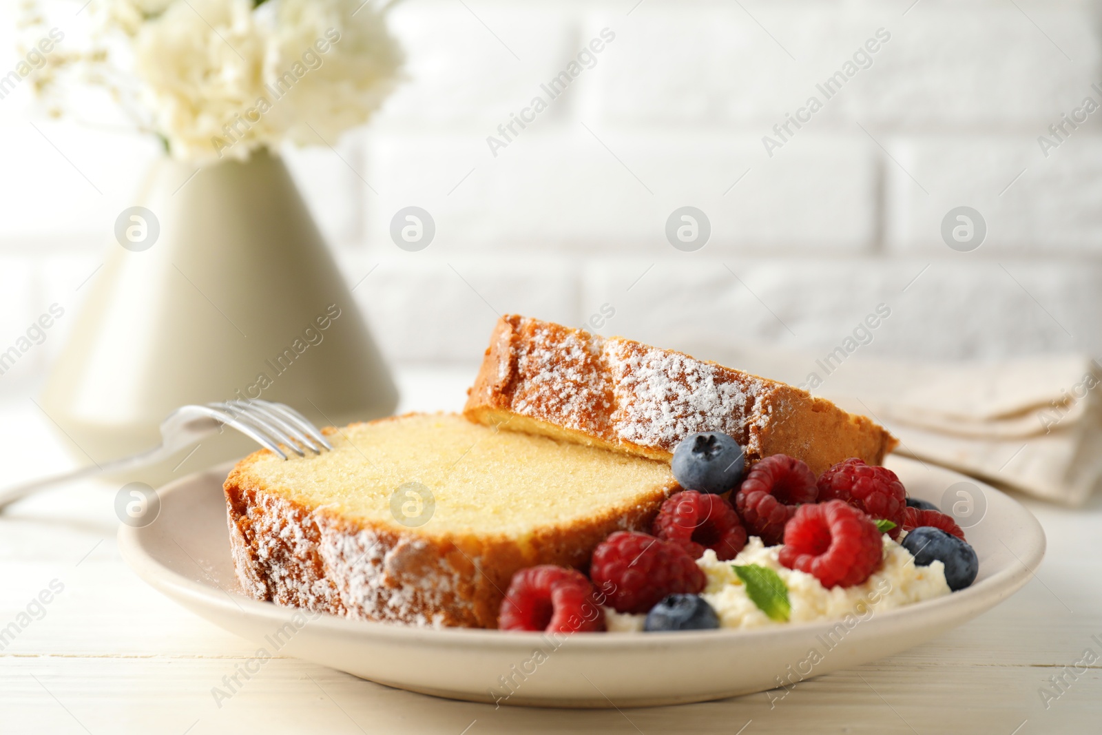 Photo of Freshly baked sponge cake, whipped cream, berries and mint on white wooden table, closeup