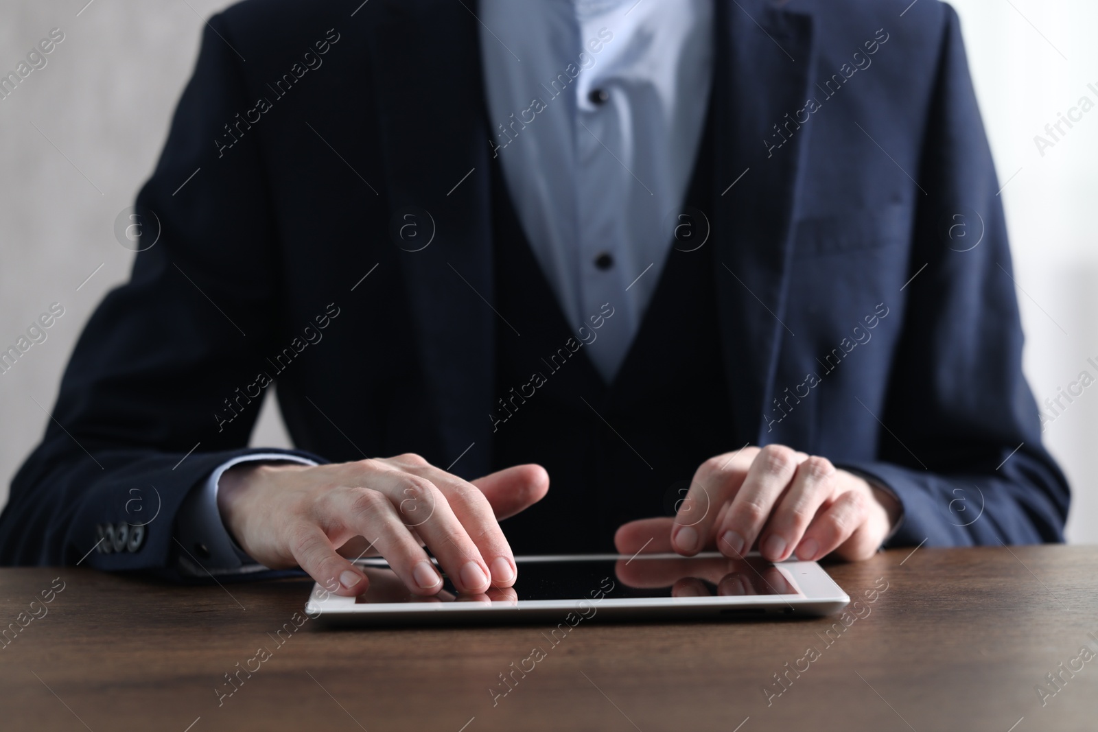 Photo of Businessman using tablet at wooden table, closeup. Modern technology