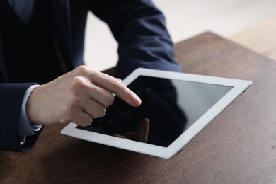 Photo of Businessman using tablet at wooden table, closeup. Modern technology