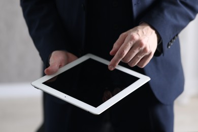 Photo of Businessman using tablet indoors, closeup. Modern technology