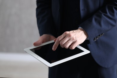 Photo of Businessman using tablet indoors, closeup. Modern technology