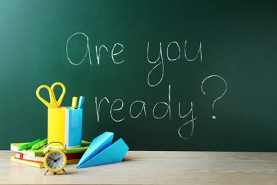 Photo of Chalkboard with question Are You Ready and stationery on wooden desk