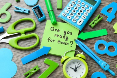 Note with question Are You Ready For Exam and stationery on wooden desk, closeup