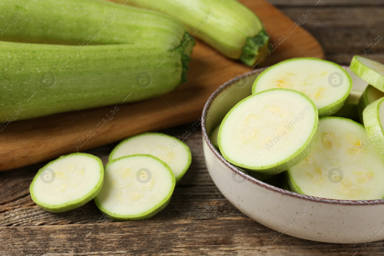 Photo of Fresh whole and cut zucchinis on wooden table, closeup