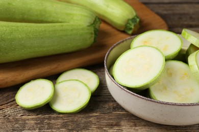 Photo of Fresh whole and cut zucchinis on wooden table, closeup