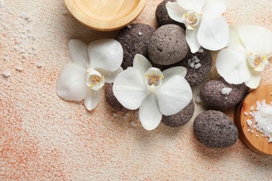 Spa stones, sea salt and beautiful orchid flowers on beige textured background, flat lay