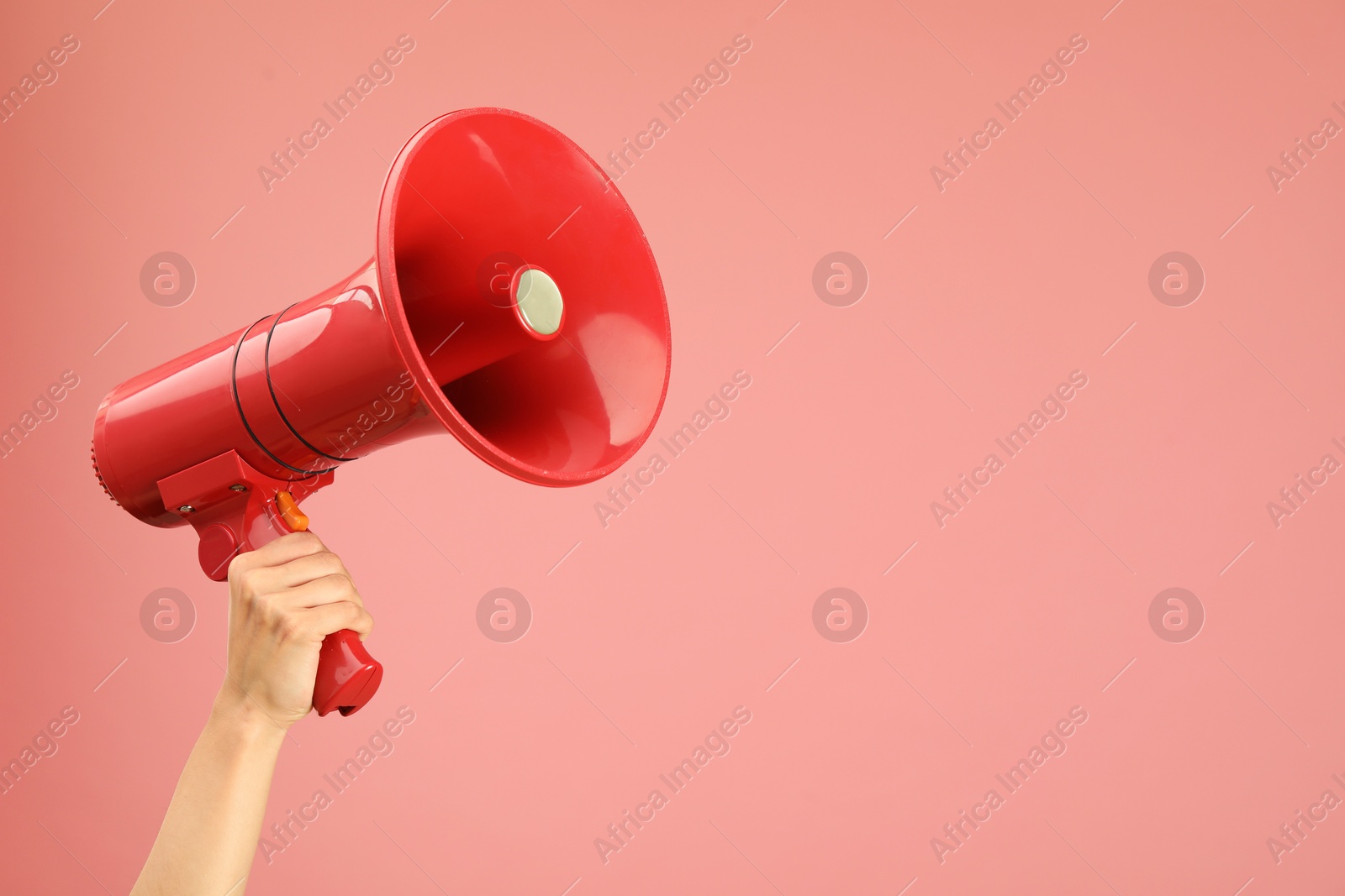 Photo of Woman holding megaphone speaker on pink background, closeup. Space for text