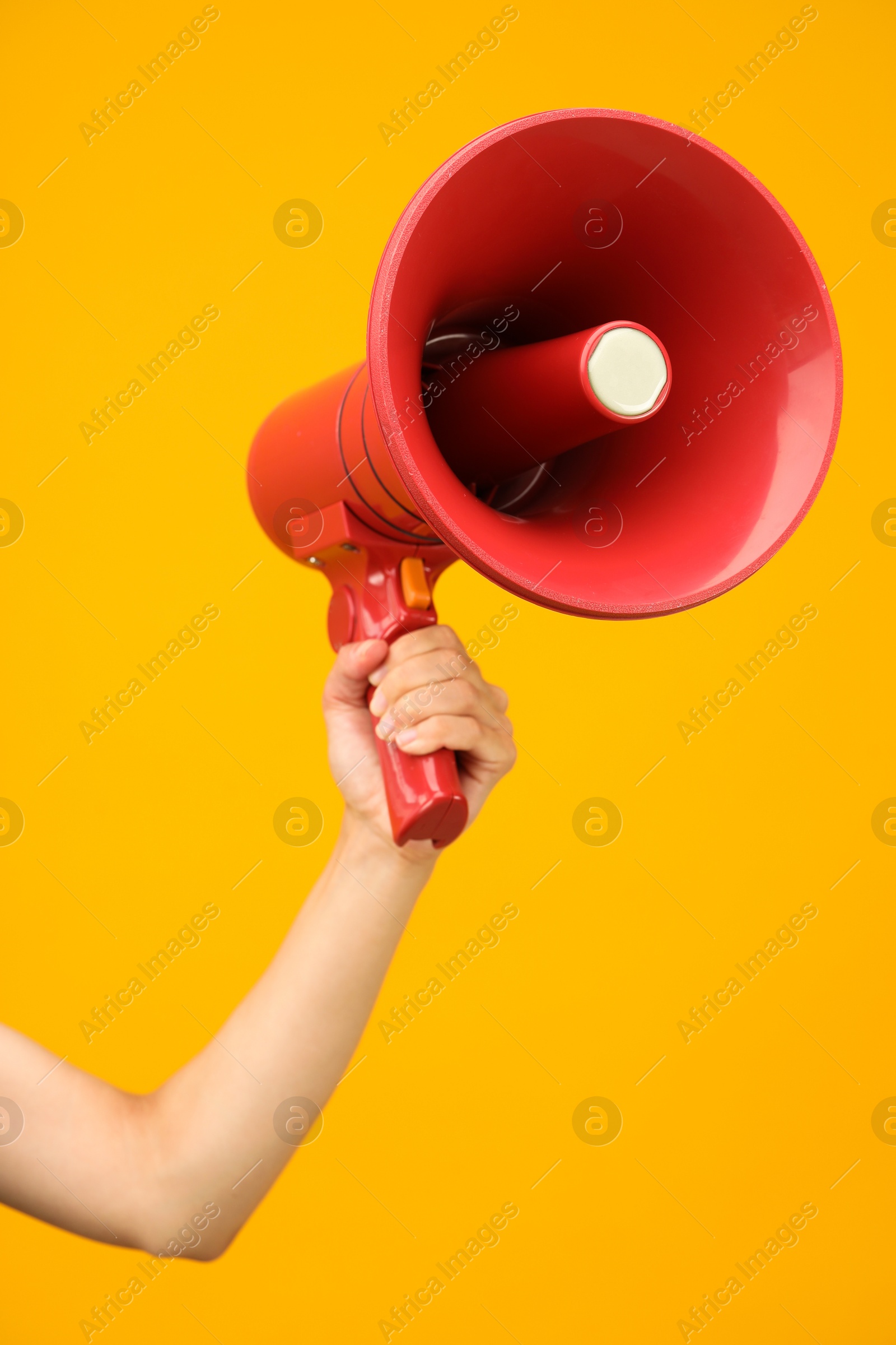 Photo of Woman holding megaphone speaker on orange background, closeup